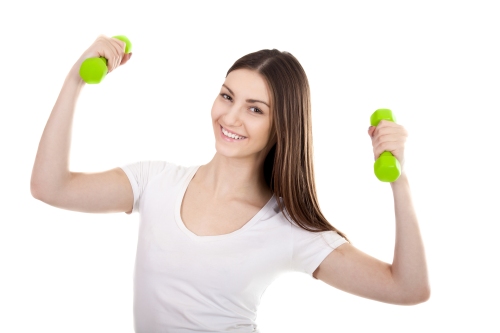 Smiling young woman trains biceps with dumbbells